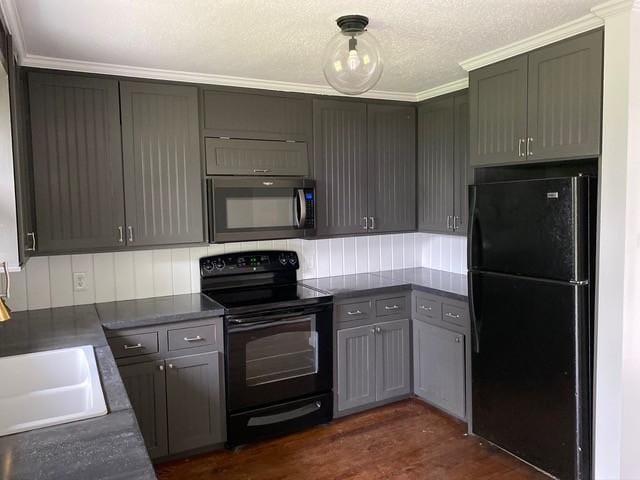 kitchen with a sink, dark wood-style floors, black appliances, tasteful backsplash, and dark countertops