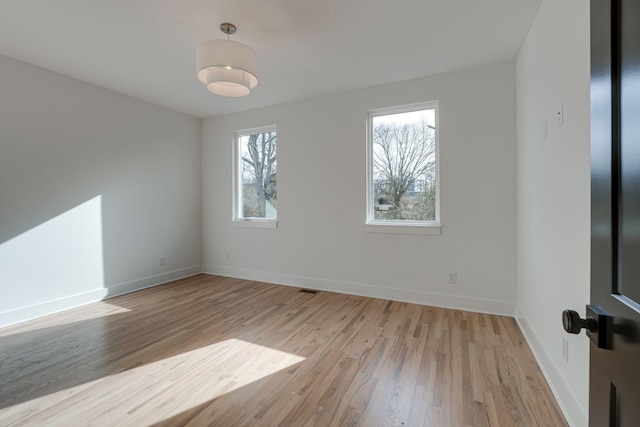 unfurnished room with light wood-style flooring, visible vents, and baseboards