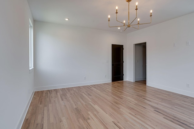 unfurnished room with light wood-type flooring, a notable chandelier, baseboards, and recessed lighting