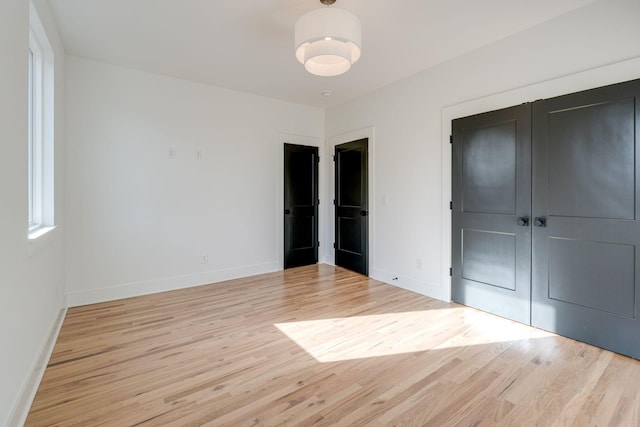 unfurnished bedroom with light wood finished floors, baseboards, and a closet