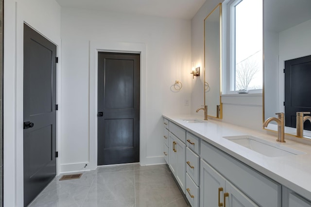 full bath with double vanity, baseboards, visible vents, and a sink