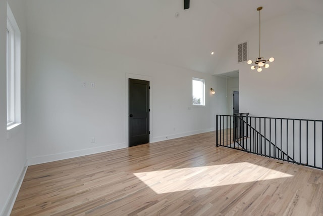 spare room featuring light wood-style floors, baseboards, visible vents, and a notable chandelier