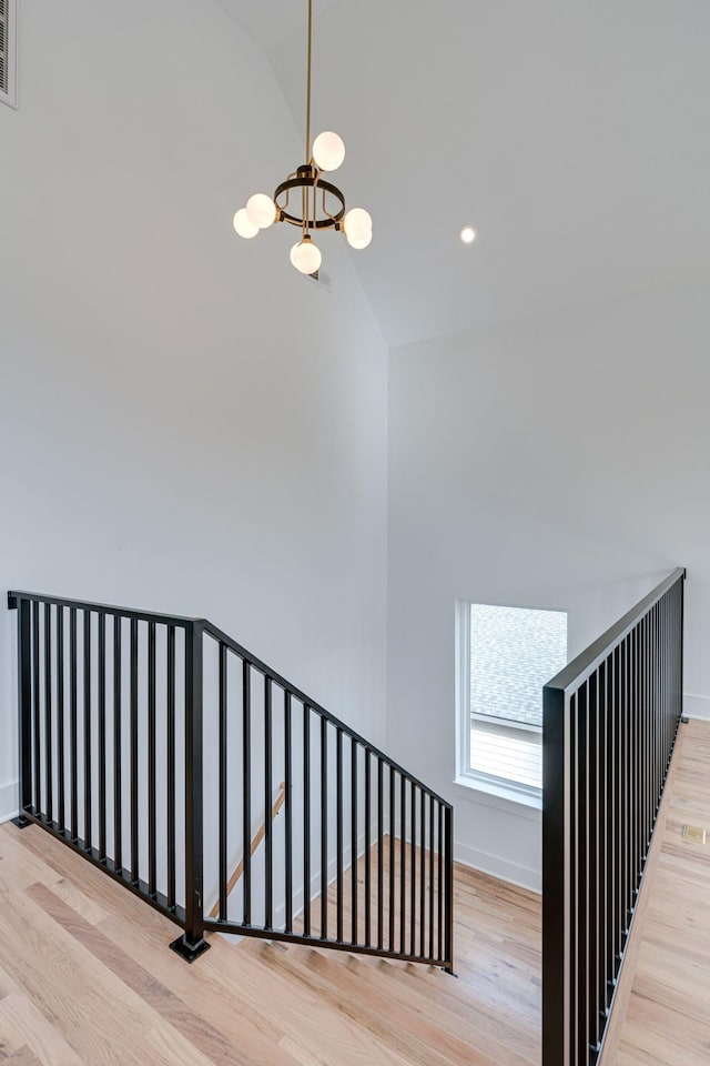 staircase featuring baseboards, a chandelier, wood finished floors, high vaulted ceiling, and recessed lighting