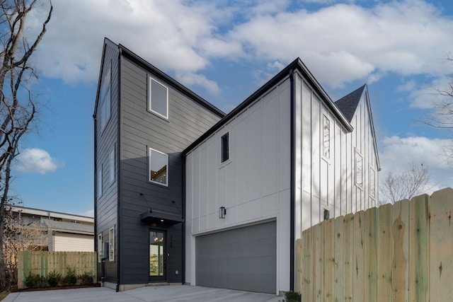 view of front of home featuring a garage, fence, and concrete driveway