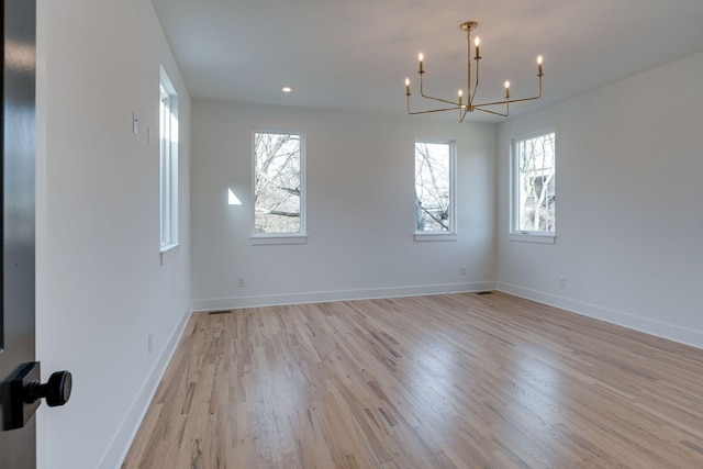 unfurnished room with light wood finished floors, baseboards, a notable chandelier, and recessed lighting