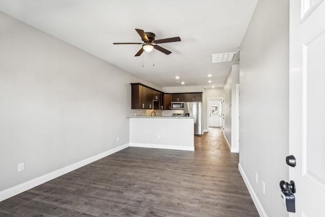 kitchen with stainless steel appliances, light countertops, dark brown cabinetry, a peninsula, and baseboards