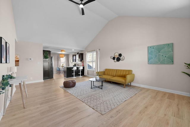 living room featuring light wood-style floors, ceiling fan, high vaulted ceiling, and baseboards