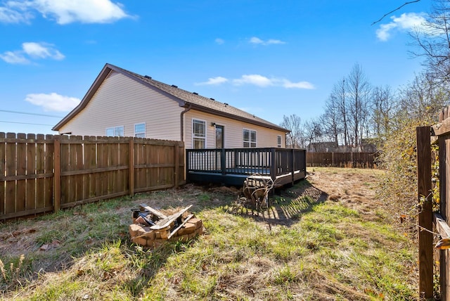 rear view of property featuring a fenced backyard, a fire pit, and a wooden deck