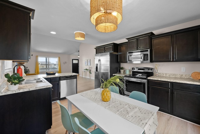 kitchen featuring light wood finished floors, stainless steel appliances, a sink, and light countertops