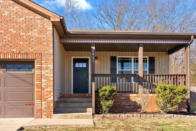 entrance to property with an attached garage, a porch, board and batten siding, and brick siding