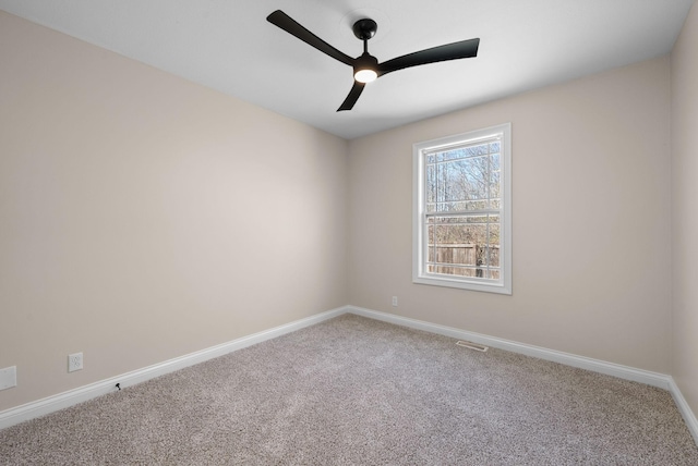 empty room with carpet flooring, ceiling fan, visible vents, and baseboards