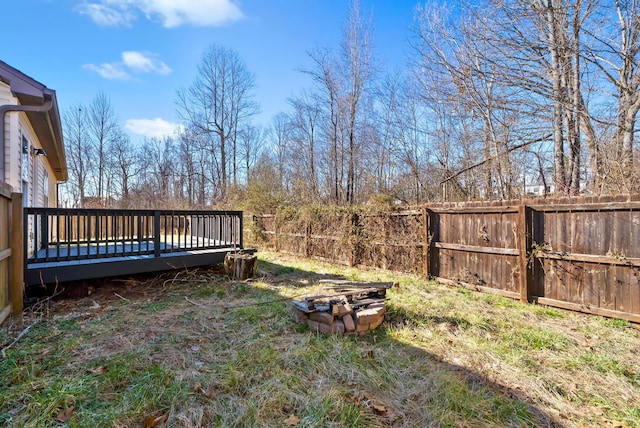 view of yard featuring a deck, an outdoor fire pit, and a fenced backyard