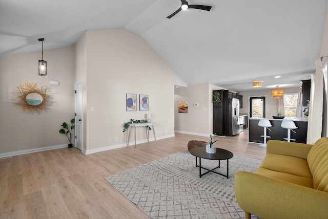 living room with high vaulted ceiling, light wood-style flooring, a ceiling fan, and baseboards