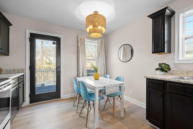 dining room with baseboards, light wood-style floors, and a healthy amount of sunlight