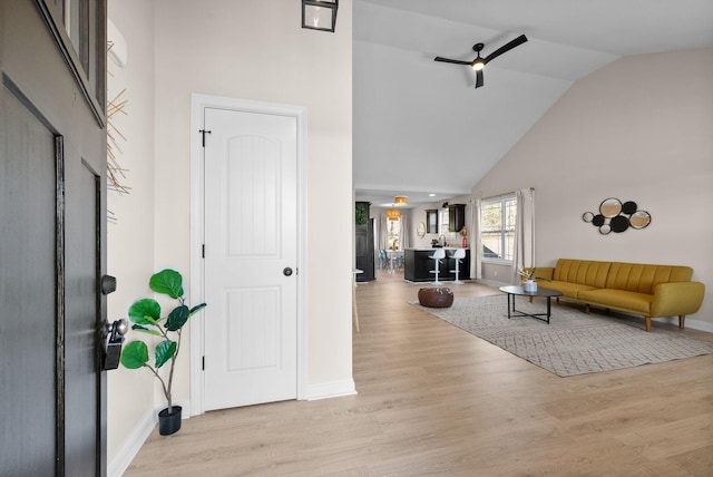 entryway with high vaulted ceiling, light wood-type flooring, ceiling fan, and baseboards