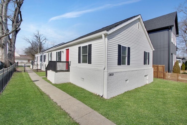 view of side of property featuring crawl space, fence private yard, a lawn, and brick siding