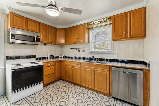 kitchen featuring stainless steel appliances, brown cabinetry, a sink, and tile countertops