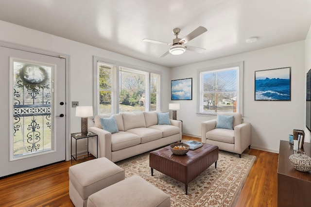 living room featuring ceiling fan, baseboards, and wood finished floors