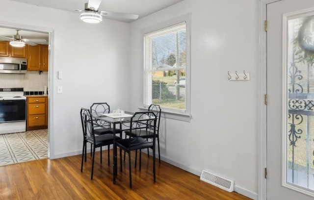 dining room with ceiling fan, light wood finished floors, visible vents, and baseboards