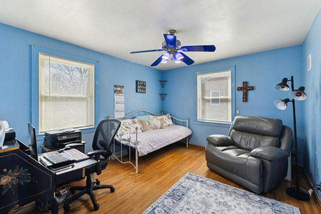 bedroom with multiple windows, ceiling fan, and wood finished floors