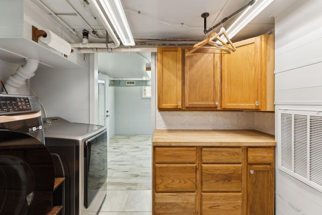 clothes washing area with independent washer and dryer and cabinet space