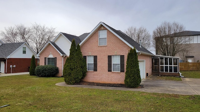 exterior space with brick siding, concrete driveway, a sunroom, an attached garage, and a front yard