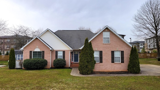 traditional home featuring a shingled roof, brick siding, fence, and a front lawn