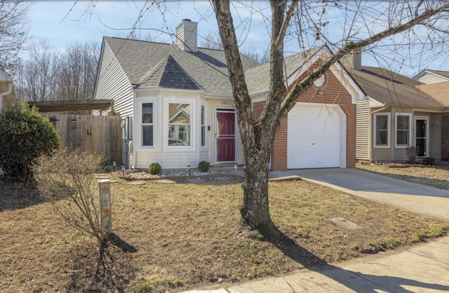 view of front of home featuring an attached garage, a shingled roof, brick siding, fence, and driveway