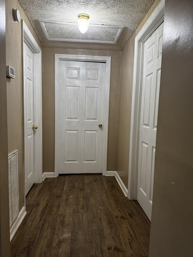 corridor featuring baseboards, visible vents, and dark wood-type flooring