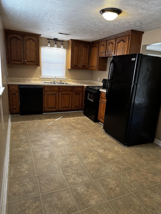 kitchen with a textured ceiling, black appliances, a sink, and light countertops