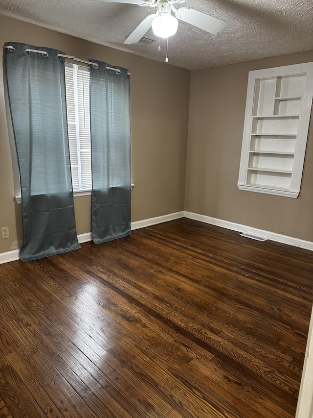 empty room with visible vents, a textured ceiling, and wood finished floors