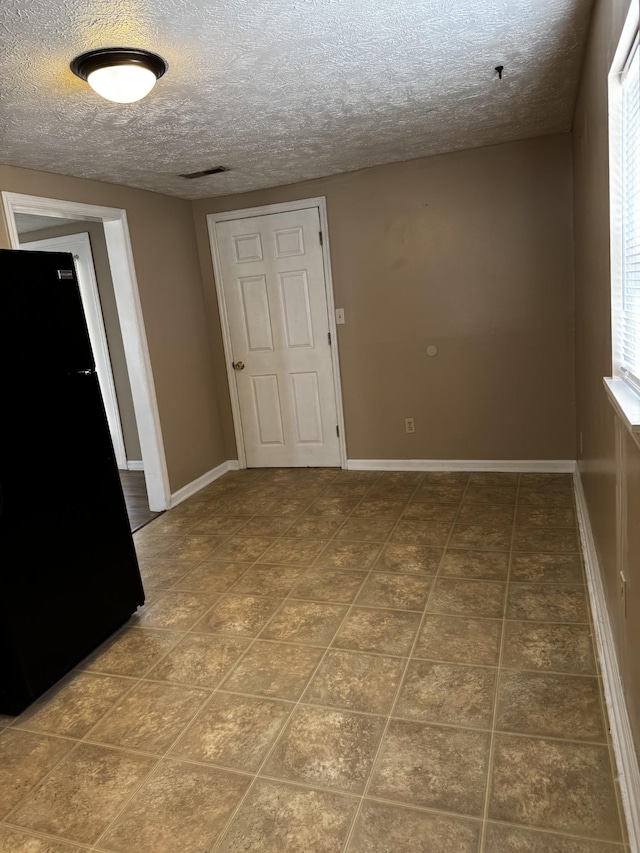 unfurnished room with visible vents, baseboards, and a textured ceiling