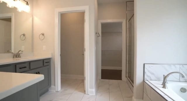 full bathroom featuring a garden tub, vanity, baseboards, a spacious closet, and a shower stall