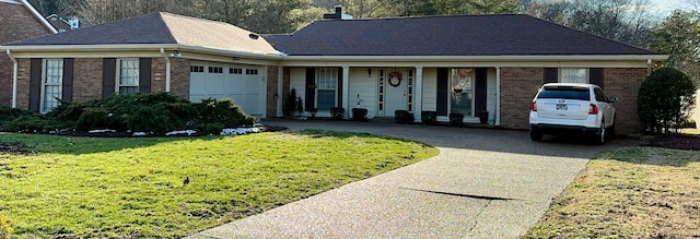 ranch-style house with driveway, a chimney, an attached garage, a front lawn, and brick siding