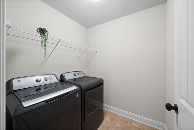 washroom with laundry area, washing machine and clothes dryer, and baseboards