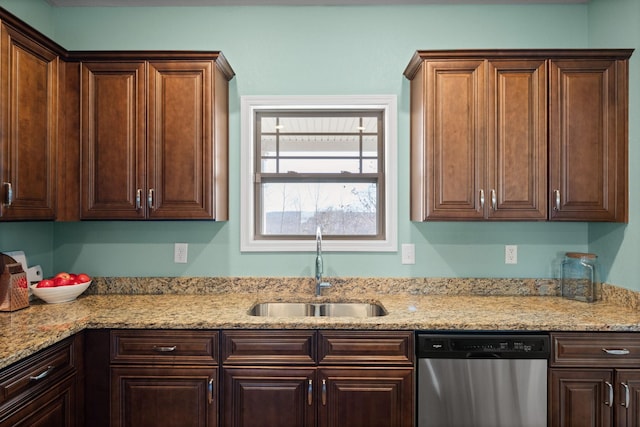 kitchen with dark brown cabinetry, a sink, stainless steel dishwasher, and light stone countertops