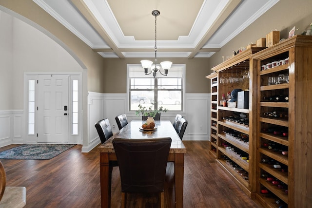 dining space featuring an inviting chandelier, dark wood finished floors, and a wainscoted wall