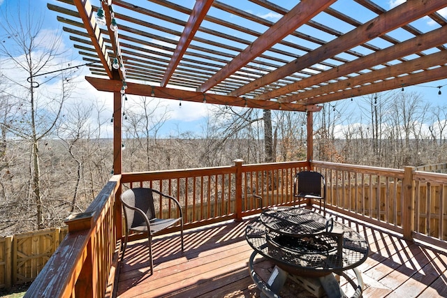 wooden deck with a view of trees and a pergola