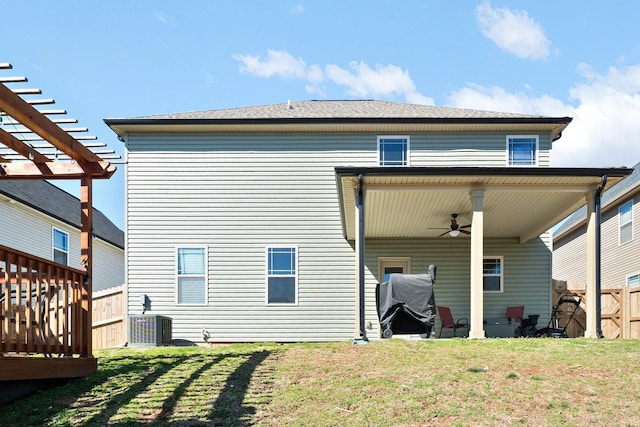 rear view of property with fence, a pergola, a ceiling fan, and a yard