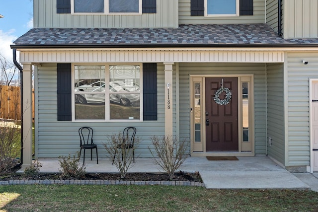 view of exterior entry featuring board and batten siding, covered porch, and roof with shingles