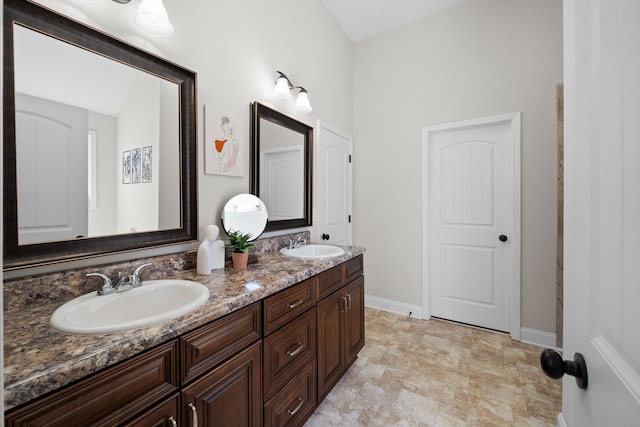 bathroom with double vanity, baseboards, and a sink