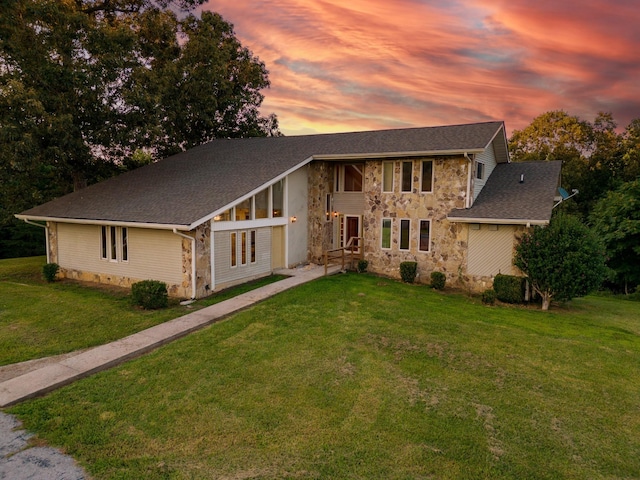 view of front of property featuring stone siding, roof with shingles, and a yard