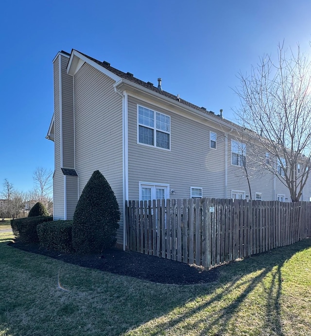 view of side of property featuring a lawn and fence