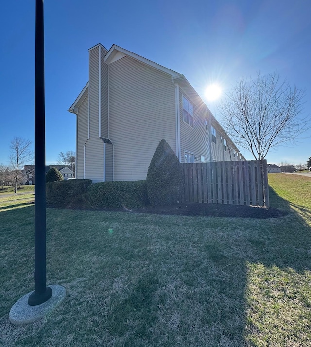 view of home's exterior featuring a lawn and fence