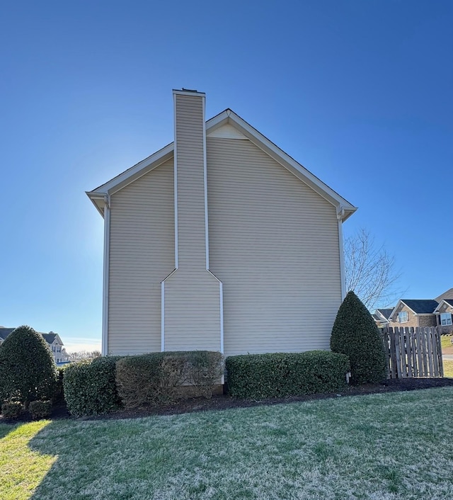 view of home's exterior featuring a yard, a chimney, and fence