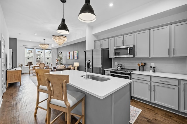 kitchen with stainless steel appliances, dark wood finished floors, a sink, and gray cabinetry