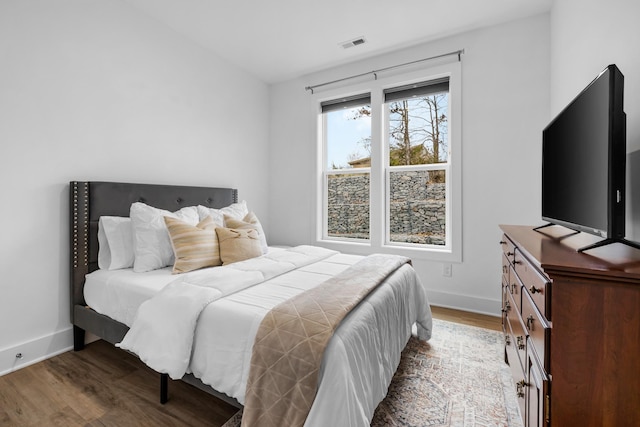 bedroom with visible vents, baseboards, and wood finished floors