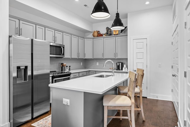 kitchen featuring dark wood finished floors, appliances with stainless steel finishes, light countertops, gray cabinetry, and a sink