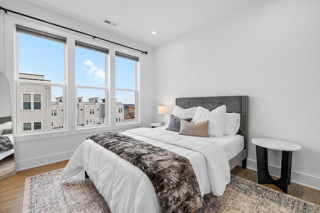 bedroom with recessed lighting, visible vents, baseboards, and wood finished floors