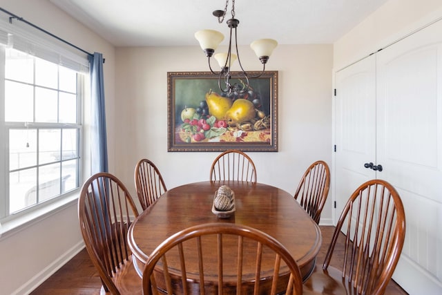 dining area featuring an inviting chandelier, plenty of natural light, baseboards, and wood finished floors